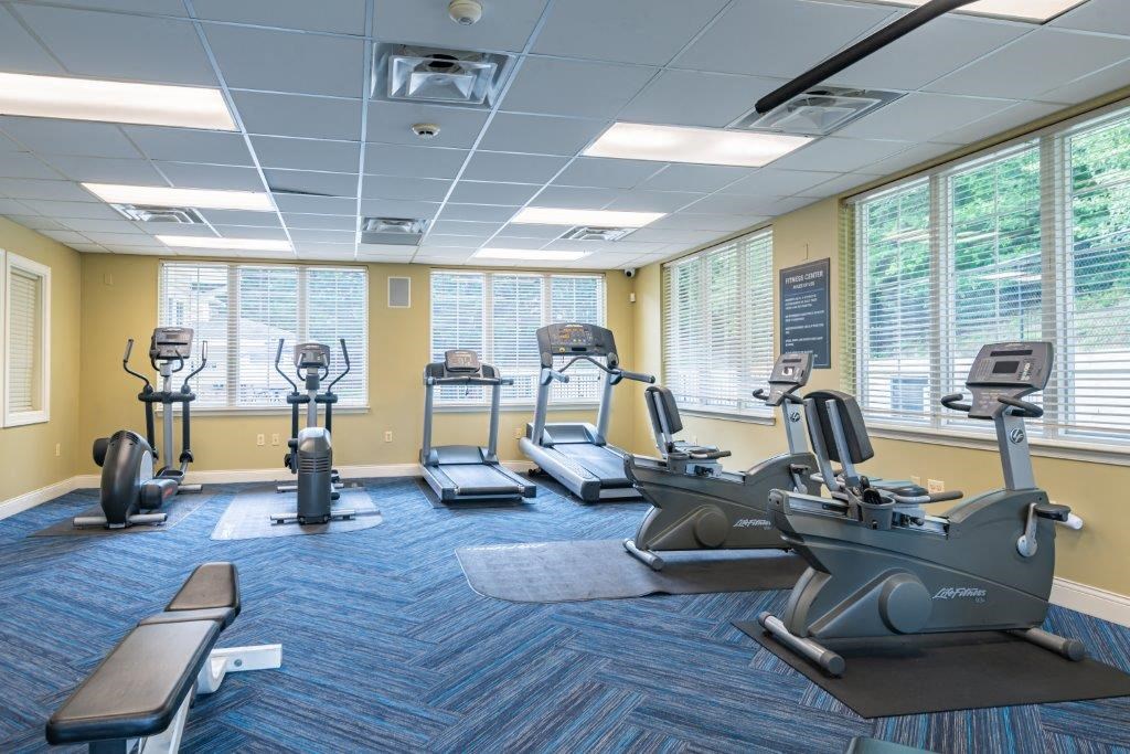 a gym with various exercise machines and windows
