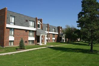 a row of brick apartment buildings on a green lawn