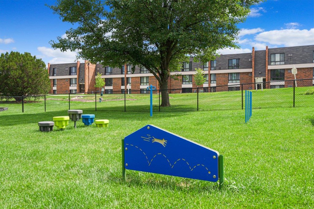 a blue sign in the middle of a field with toilets in the grass