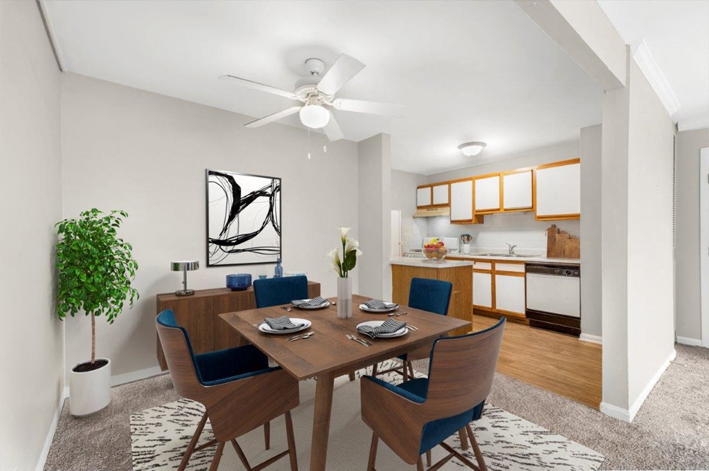 A dining room with a table set for two and a potted plant.