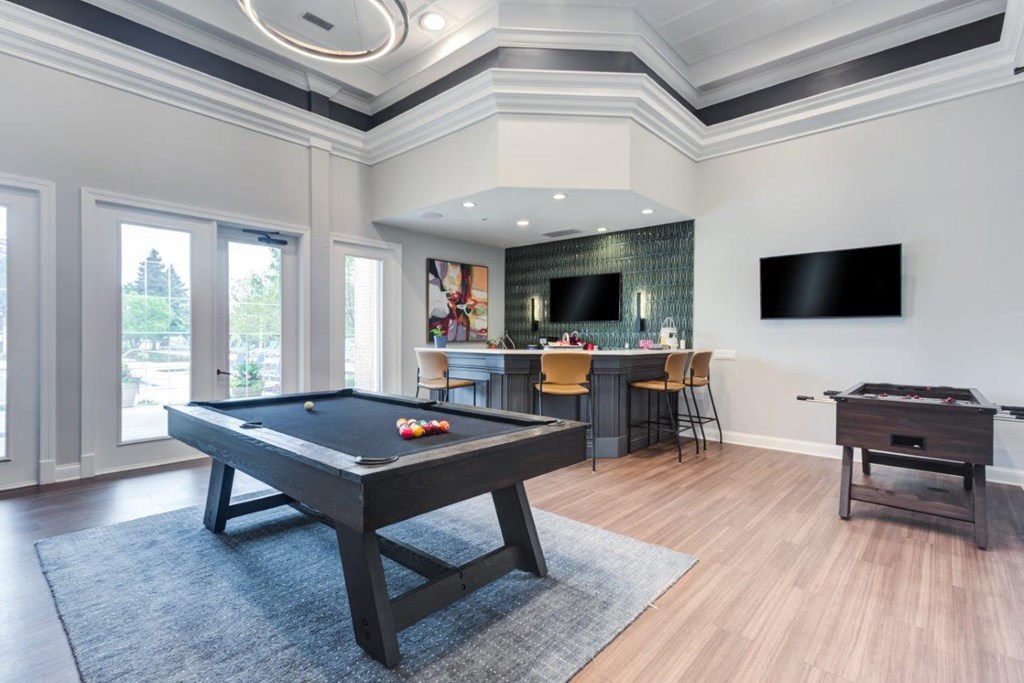 a game room with a pool table and a bar with a television