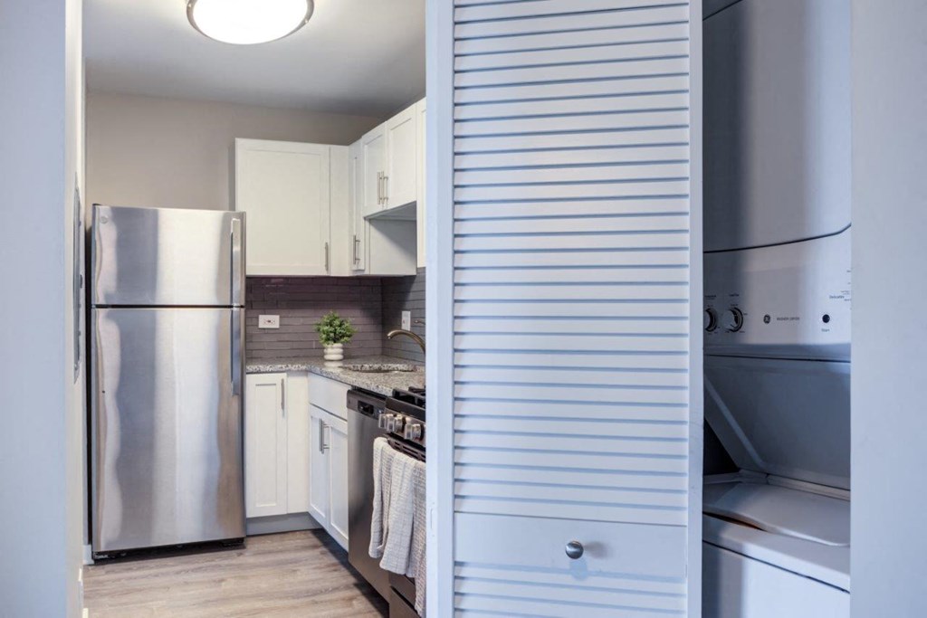 a white kitchen with a stainless steel refrigerator and a stove