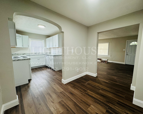 a white kitchen with hardwood floors and white cabinets