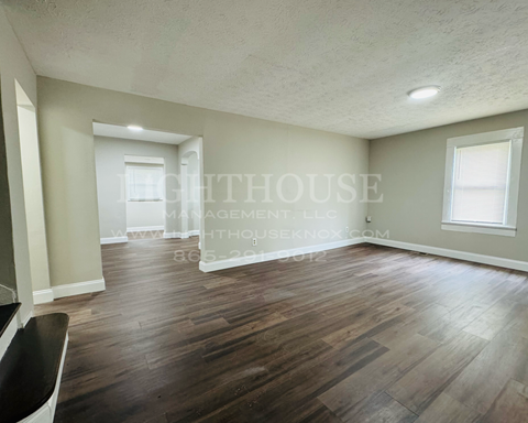 a renovated living room and dining room with hard wood floors and white walls