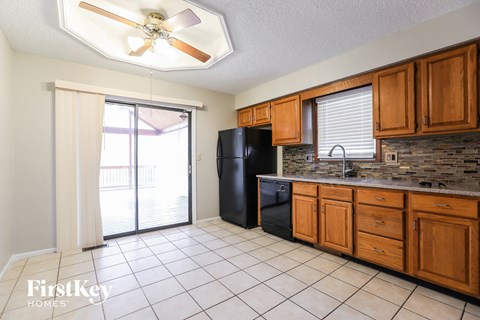 A kitchen with wooden cabinets and a black refrigerator.