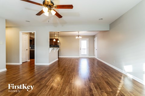 A spacious room with wooden floors and a ceiling fan.