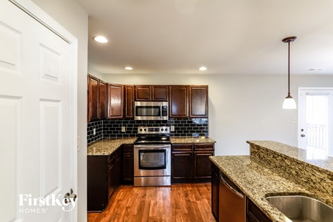 A kitchen with dark wood cabinets and a stainless steel stove top oven.