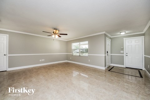A spacious room with a ceiling fan and two doors.