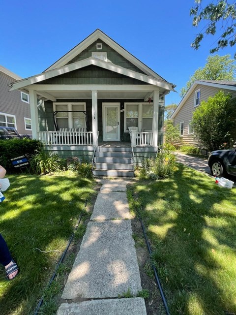 a house with a porch and a sidewalk in front of it