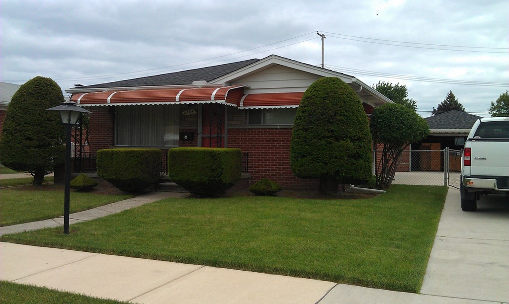 A house with a red brick exterior and a white van parked in the driveway.