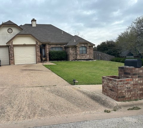a house with a driveway and lawn in front of it