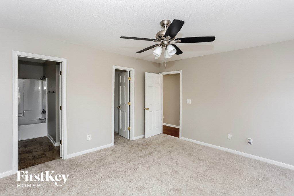 A spacious room with a ceiling fan and two doors.