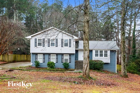 a blue and white house with a yard and trees