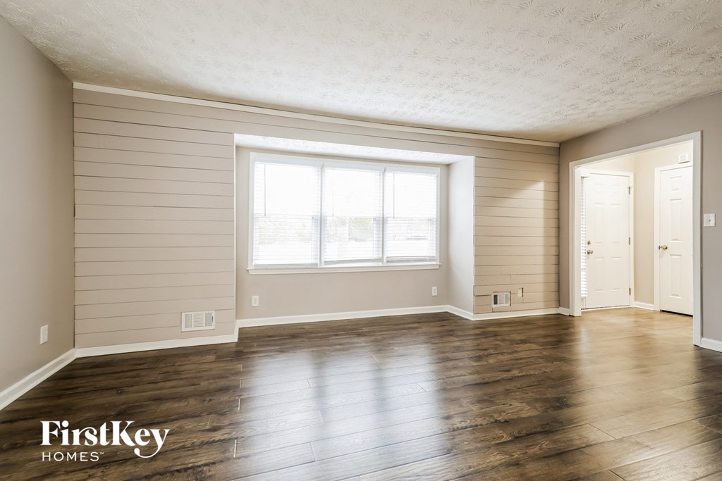 an empty living room with wood floors and a large window