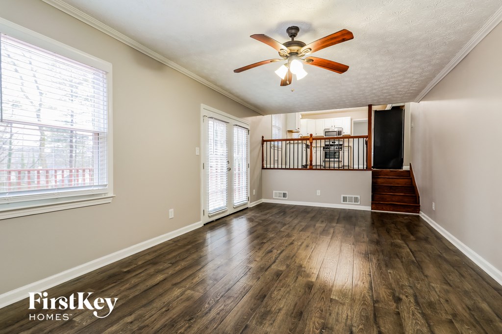 an empty living room with wood floors and a ceiling fan