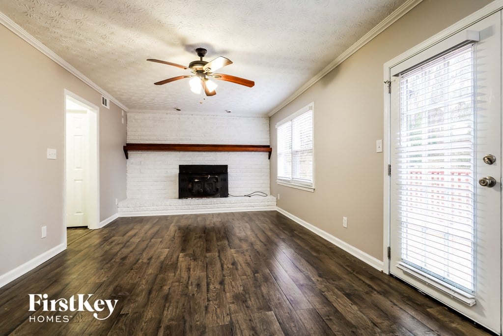 an empty living room with a fireplace and a ceiling fan