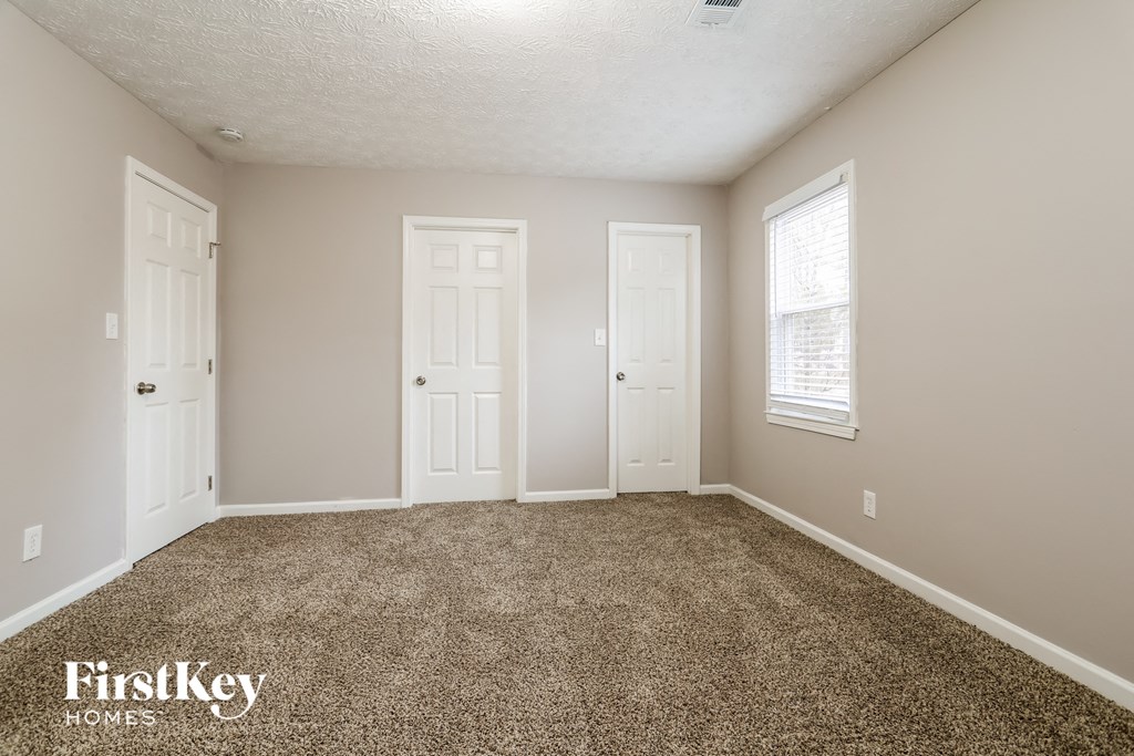 a bedroom with carpet and two doors and a window