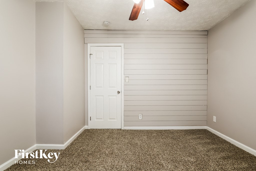 the bedroom has a white door and a carpeted floor
