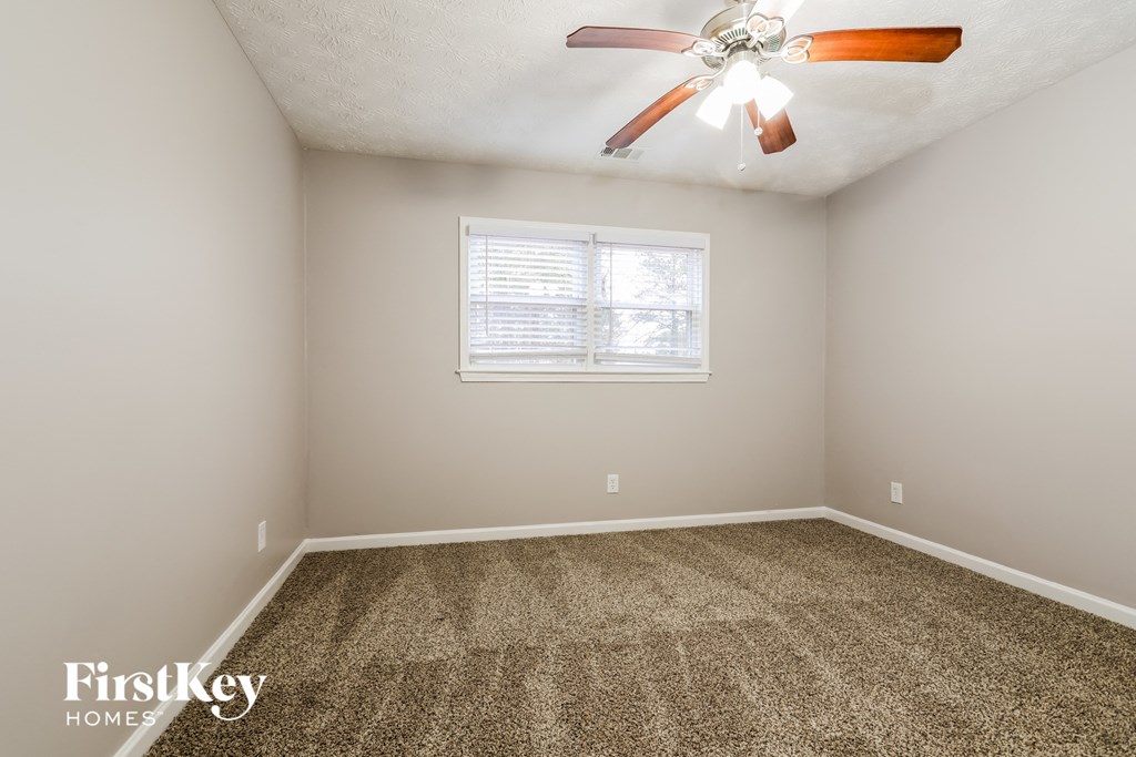 the master bedroom is spacious and has carpeting and a ceiling fan