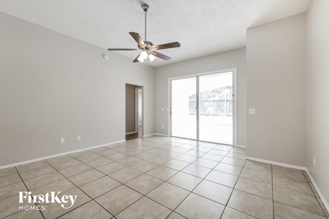 a spacious living room with tile flooring and a ceiling fan