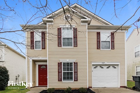 A two-story house with a red door and garage door.