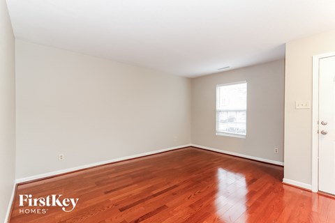 A room with wooden flooring and a window with a white frame.