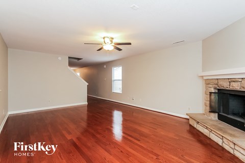 A spacious living room with wood flooring and a fireplace.