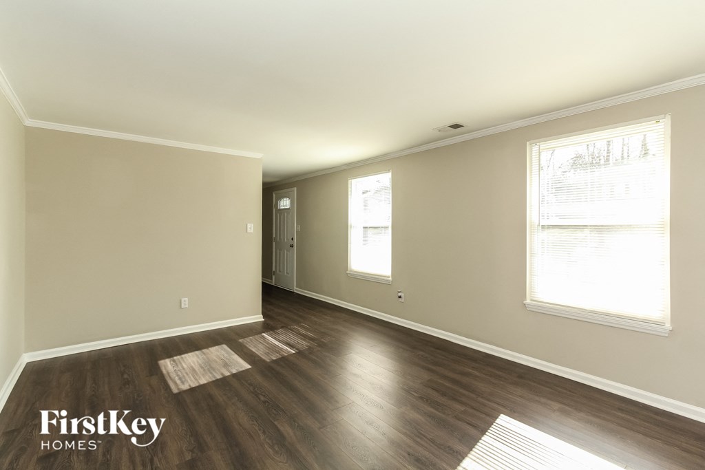 A spacious room with wooden floors and a window letting in natural light.