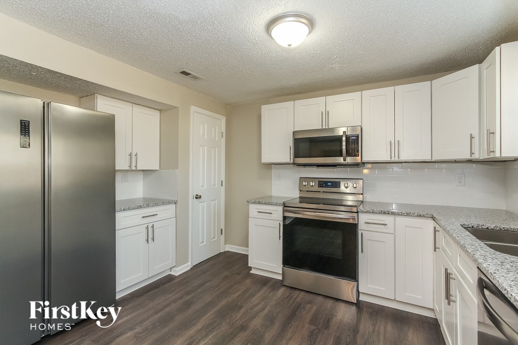 A kitchen with white cabinets and a stainless steel refrigerator.
