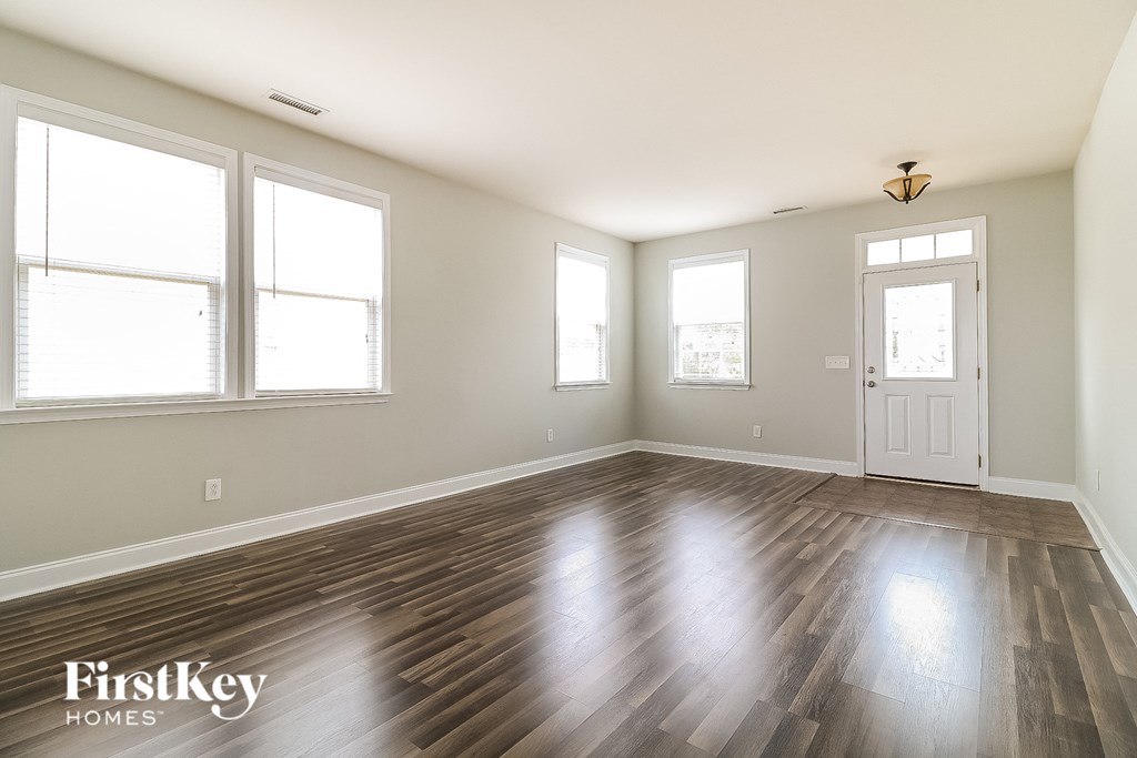 the living room of an empty house with wood floors and a white door