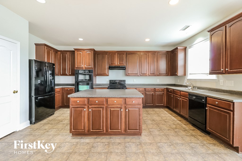 a large kitchen with black appliances and wooden cabinets