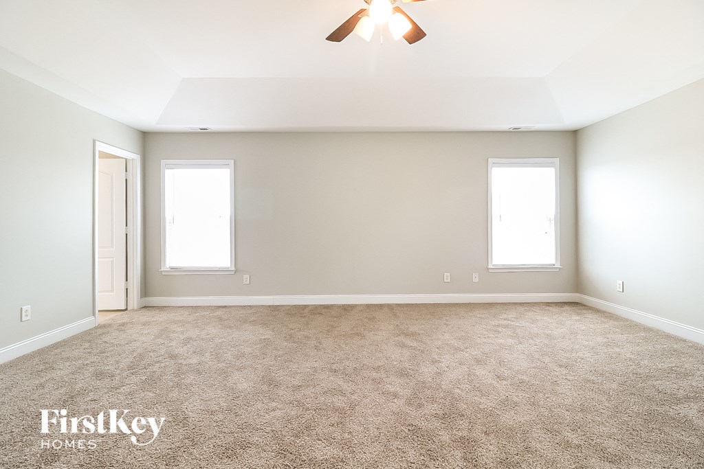a empty room with a ceiling fan and two windows