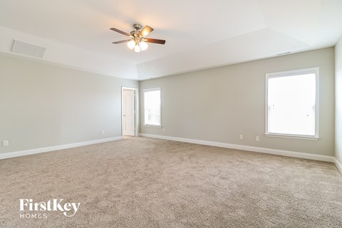 a spacious living room with carpet and a ceiling fan