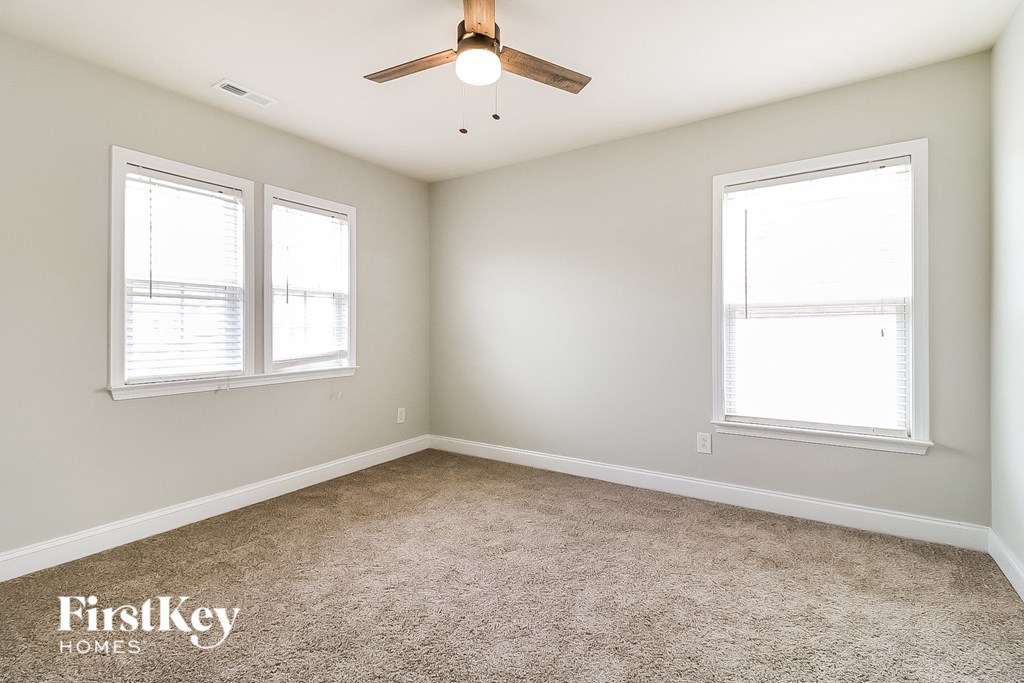 a bedroom with two windows and a ceiling fan