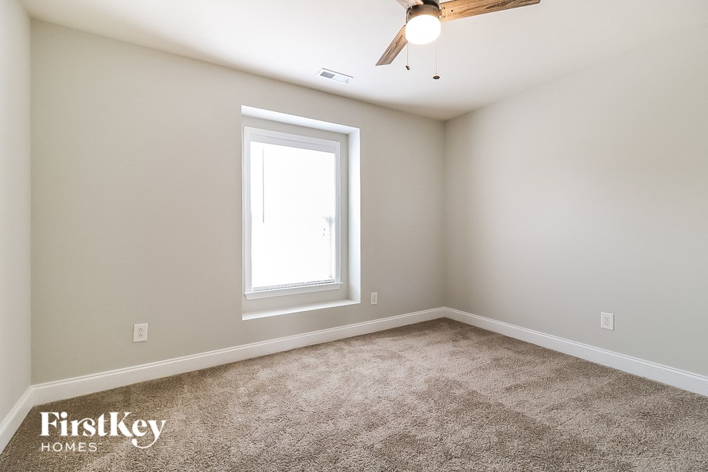 a bedroom with carpet and a window and a ceiling fan