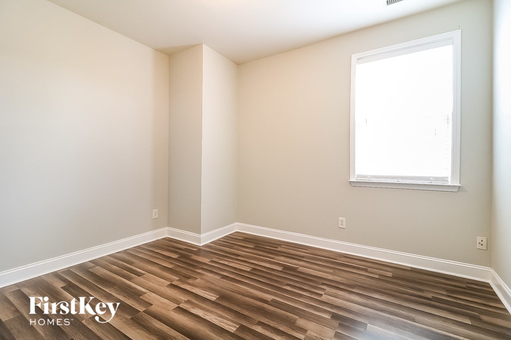 the second bedroom with wood flooring and a window