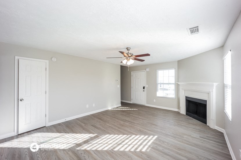 an empty living room with a ceiling fan and a fireplace