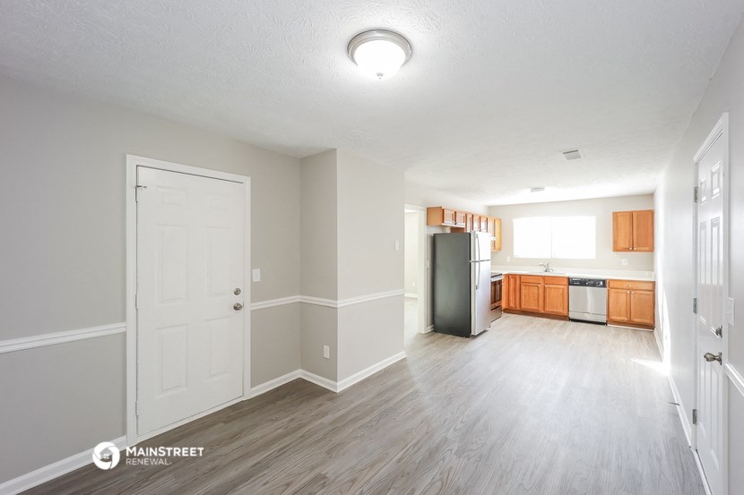 an empty living room and kitchen with white walls and wood flooring