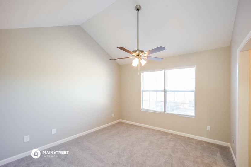 an empty room with a ceiling fan and a window
