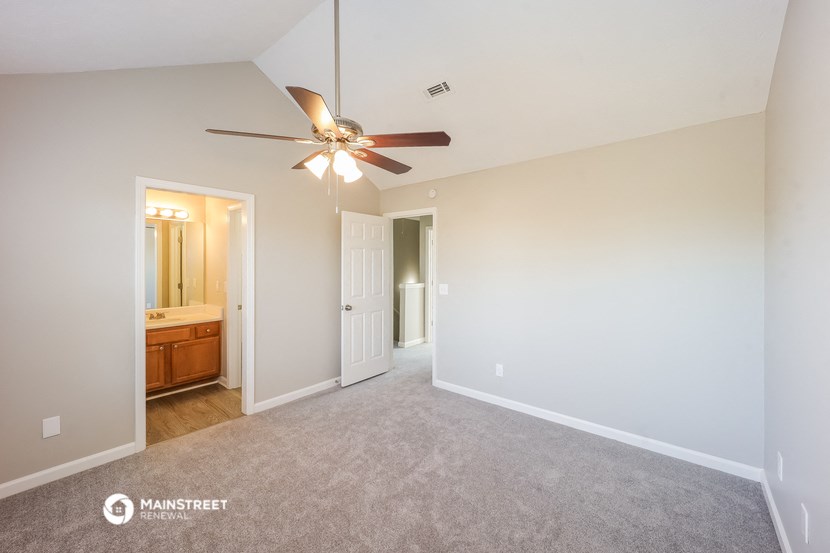 an empty living room with a ceiling fan and a bathroom
