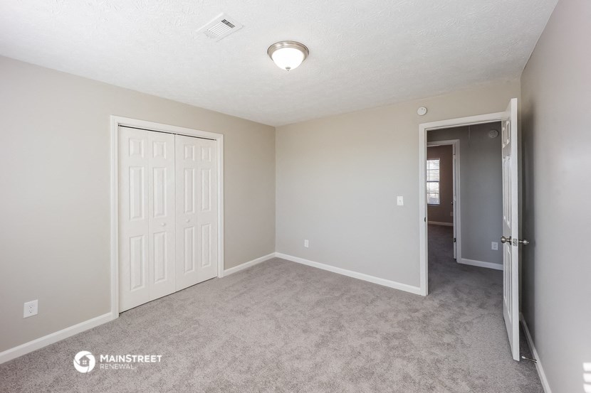 a bedroom with a door to a hallway and a closet