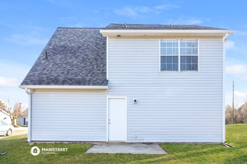 a small white rental house with a white garage door