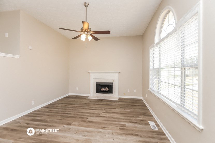 an empty living room with a ceiling fan and a fireplace