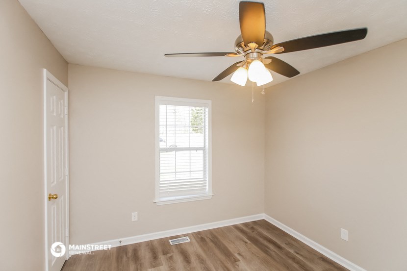 an empty room with a ceiling fan and a window