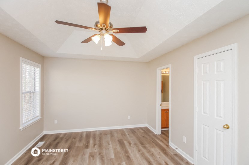 the spacious living room with a ceiling fan