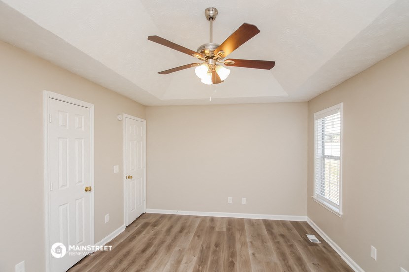 the spacious living room with ceiling fan and closet