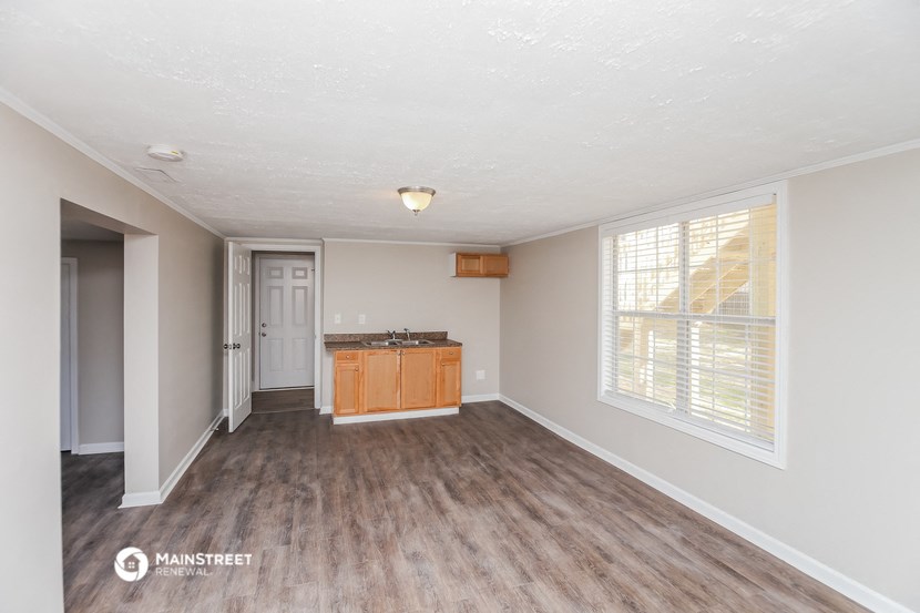 the living room and kitchen of an empty house with wood flooring