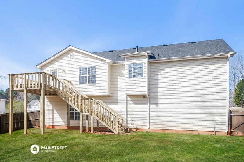 the back of a white house with a wooden deck