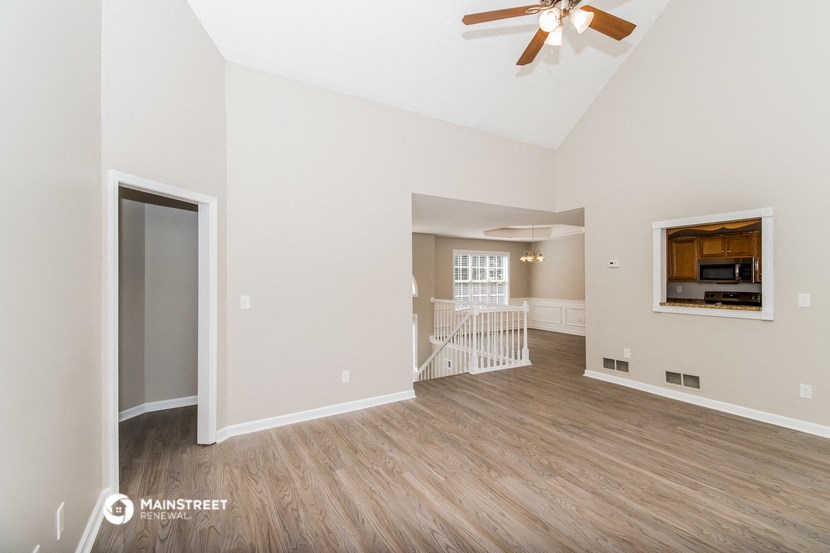 a living room with a ceiling fan and a door to a staircase