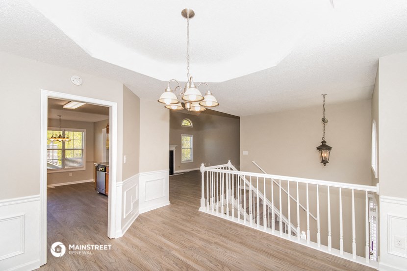 the entryway of a house with a white staircase and a hallway with a window